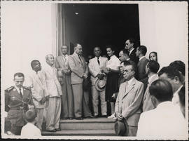 Clemente Mariani e outros sendo recepcionados por uma aluna em frente a um prédio não identificado